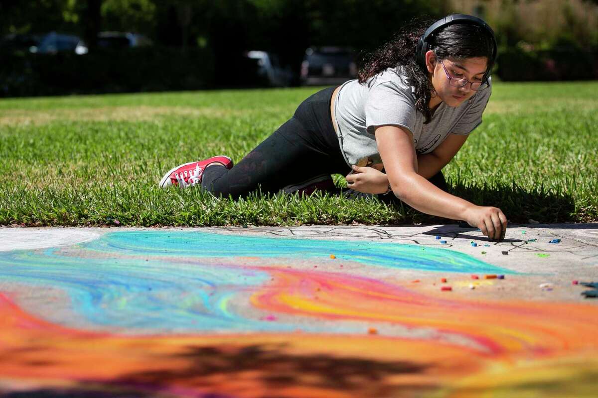 Madison Garcia, 13, draws on the sidewalk with chalk Saturday at Landa Library. in San Antonio, Texas, on Oct. 9, 2021.