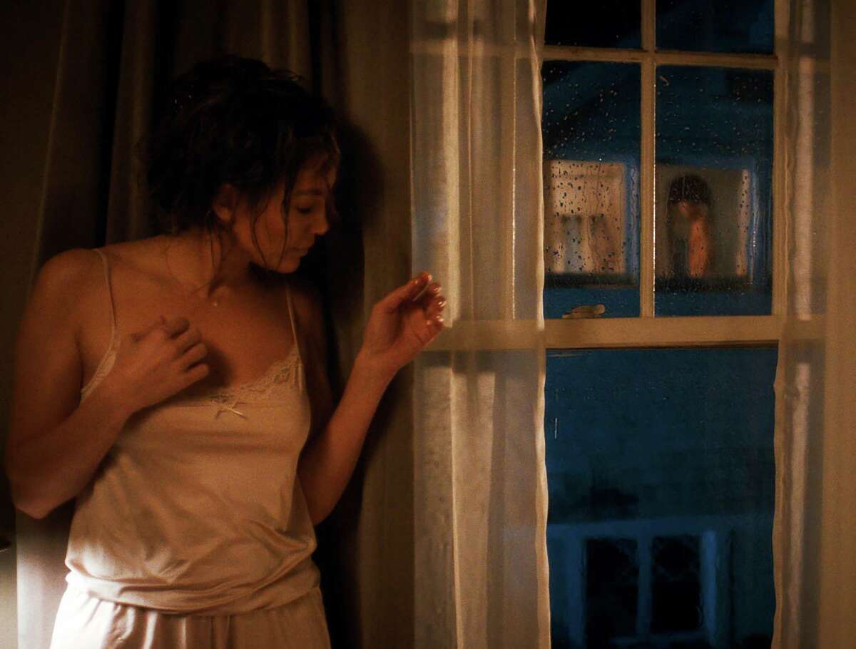 Девушка подглядывает за своим парнем в окно и снимает его на камеру