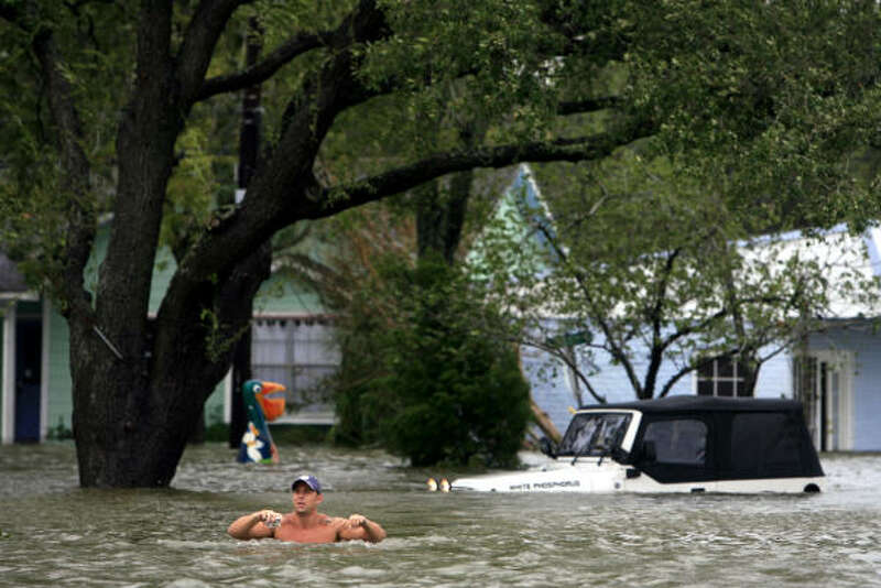 A photo of a man standing in chest-high water with a partially submerged Jeep in the background