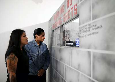 Daniel Casillas, 22, and his sister, Elisabeth Casillas, 28, look at a facsimile solitary confinement cell built by Martin Leyva as they attend the 2nd Annual Project Rebound Mural Celebration called "Incarceration to Liberation" at San Francisco State University.