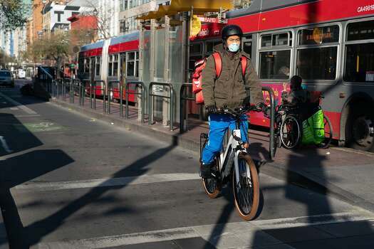 One bicyclist wearing a protective mask waits at a light on Market St. on Thursday, March 19, 2020, in San Francisco, California.
