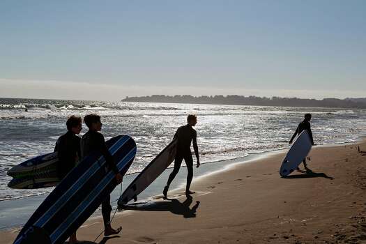 Four surfers drag their boards behind them as they walk on Stinson Beach in Marin County on Saturday, May 23, 2015.