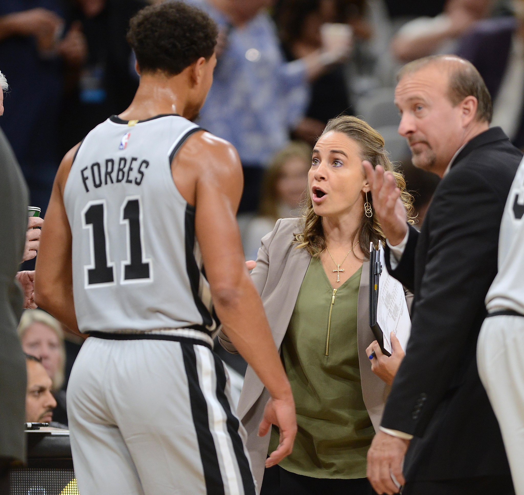 Becy Hammon giving Spurs guard Bryn Forbes direction on the sidelines of an NBA game.