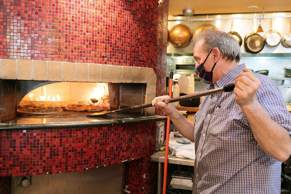 Andy Gambardella moves pizzas around in the pizza oven at Pazzo in San Carlos.