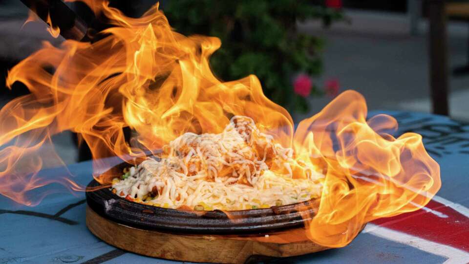 Flames erupting from a cheese-topped platter.