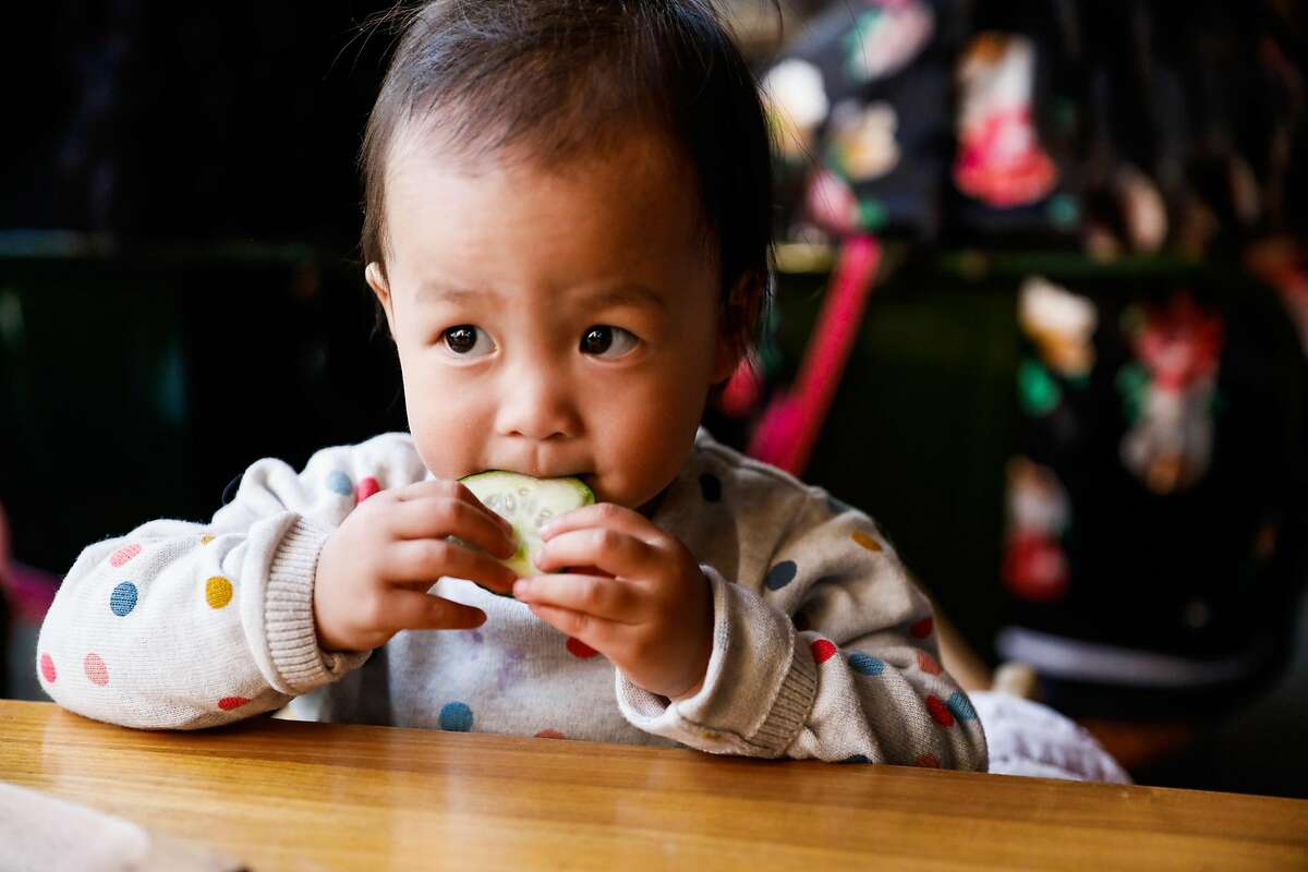 A baby eats a cucumber.