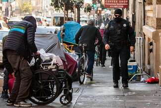 A San Francisco police officer patrols near a row of tents along Hyde Street.