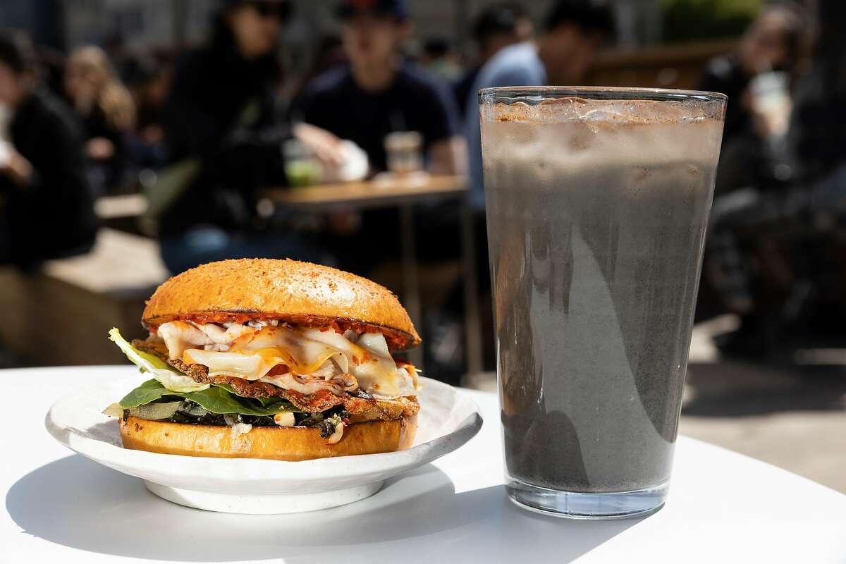 A sandwich and iced black sesame drink on a table outside