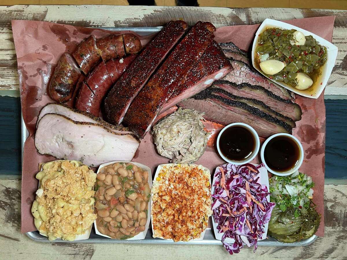 Barbecue and side options at 2M Smokehouse in San Antonio include, clockwise from top left, pork sausage with Oaxaca cheese and serranos, beef sausage, pork ribs, brisket, pickled nopales, coleslaw, Mexican street corn, beans, chicharrón macaroni and cheese, turkey and pulled pork.