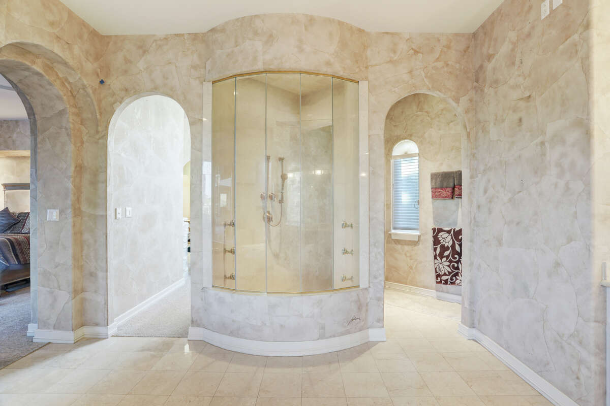 A large stand up shower is the focal point in the center of the master bathroom with ivory walls and floors. 