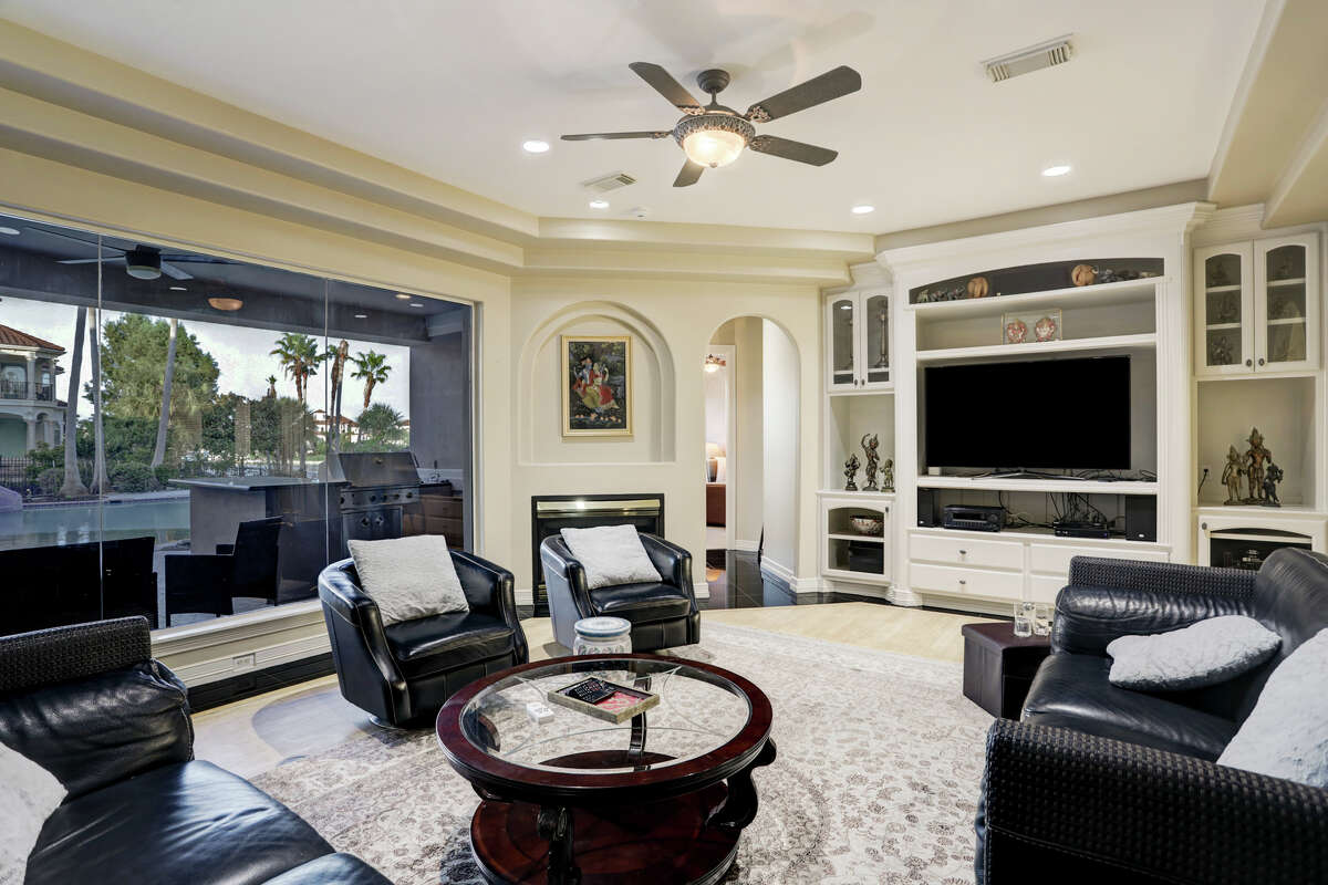 Dark leather couches and chairs with a wall of windows and entertainment center.