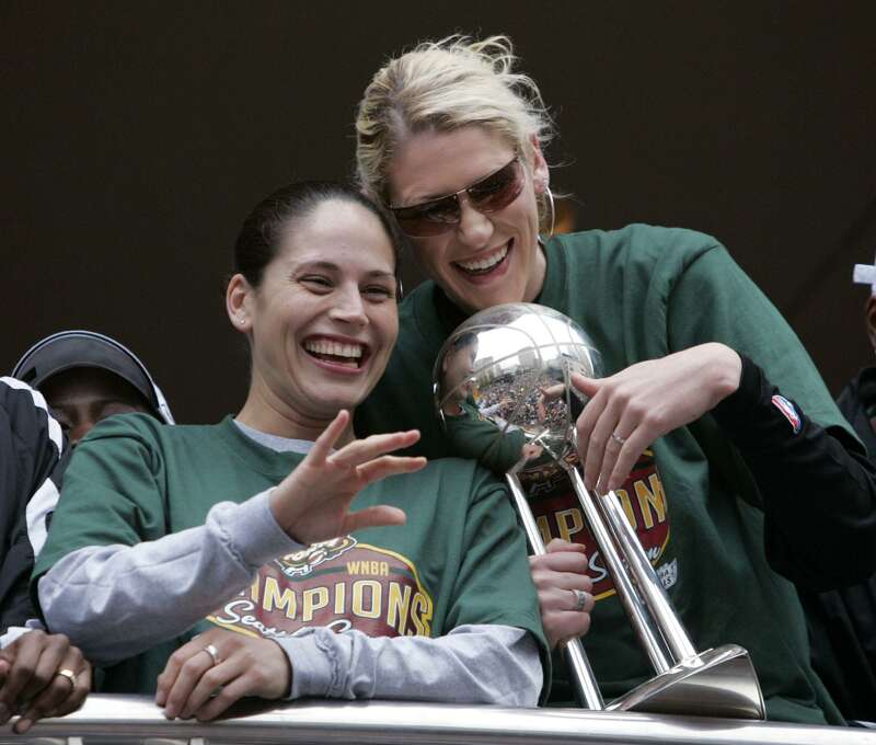 Seattle Storm's Lauren Jackson, right, holds the championship trophy as teammate Sue Bird waves at a civic rally for the team Friday, Oct. 15, 2004, in Seattle. The Storm beat the Connecticut Sun Tuesday to win the WNBA Finals. (AP Photo/Elaine Thompson)