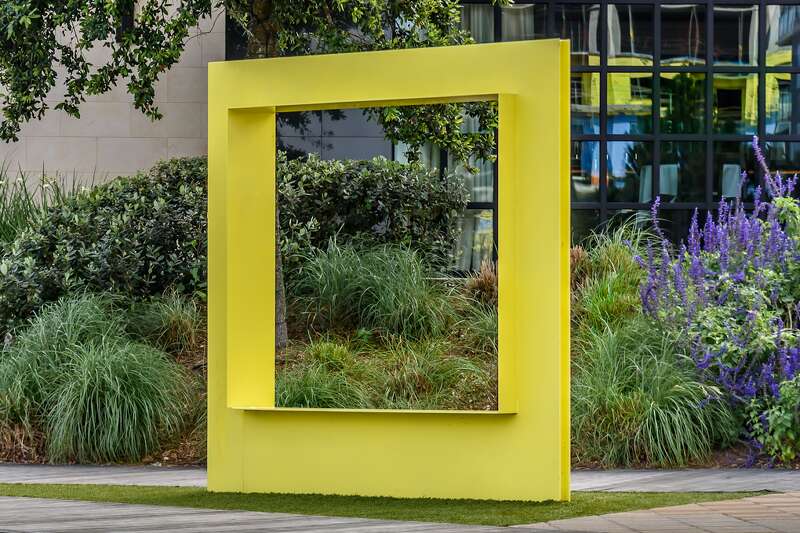 A yellow bench in the shape of a picture frame. Located in The Woodlands, Texas.