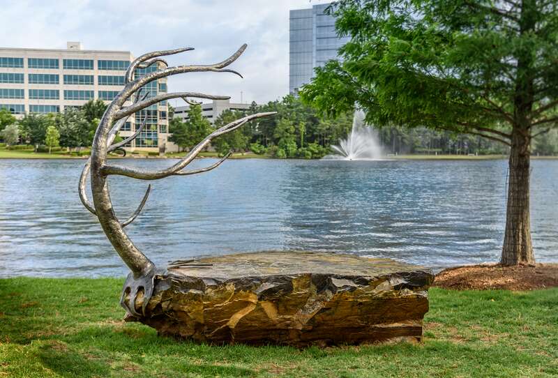 A bench in the shape of a turtle shell with a tree attatched. Located in The Woodlands, Texas.