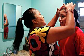 Connie Rivera, left, checks her son Cuauhtémoc’s hair after braiding it into a plait.