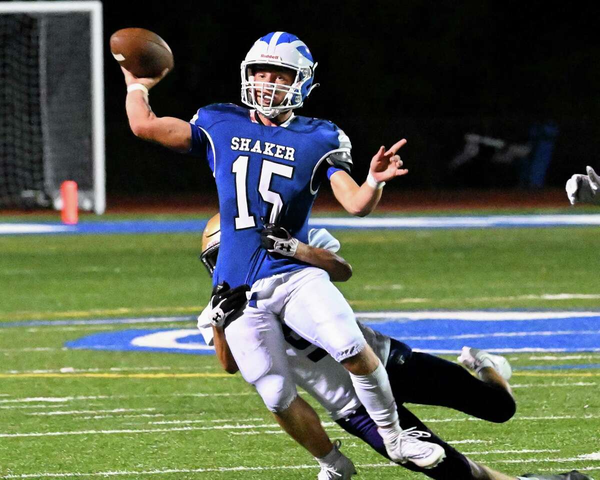 Shaker quarterback Jake Iacobaccio passes the ball while in the grasp of CBA defender Sam Smith during a game at Shaker High School.