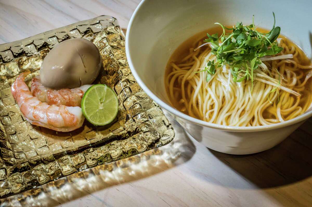 Left: shrimps and lime on a glass plate. Right: a bowl of noodles in broth.