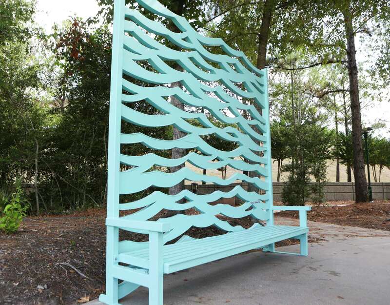 A blue bench with cutouts along the backsupport in the shapes of waves.