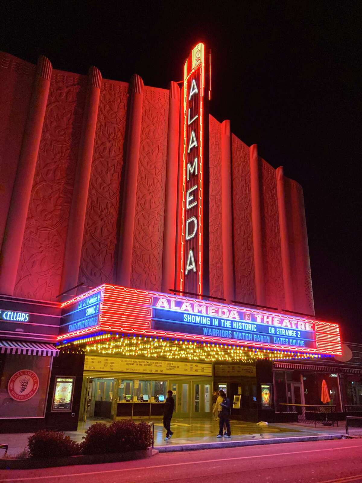 The front of the Alameda Theatre lit up at night with neon.