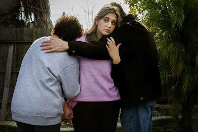 Shugufa, 23, hugs her parents, whose backs are turned so they remain anonymous.