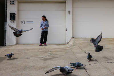 Maya Saleh feeds birds on a driveway outside her home in San Francisco.
