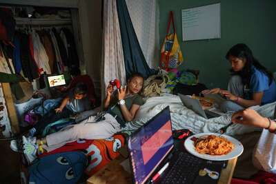 Relaxing in a San Francisco studio apartment after dinner, Mary Jane De Castro chats with her children.