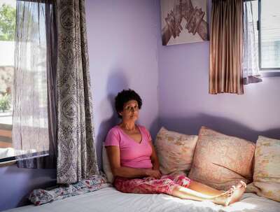 A woman seated on her bed in her bedroom