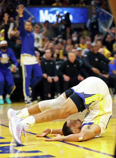 With both the back of his head and his toes touching the ground, Steph Curry is doubled over in a U-shape on the basketball court.