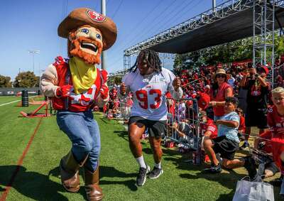 Kaila Davis dances with a 49er mascot as fans look on.