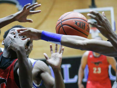 Basketball players reach their arms for a rebound.