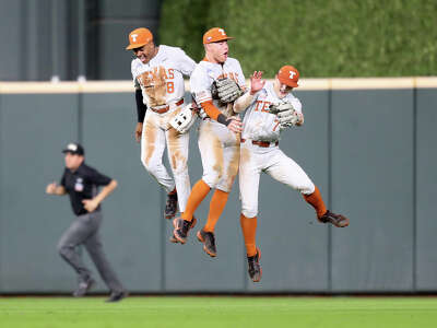 Three uniformed baseball players are side to side in the air as they have all jumped up in celebration at their win 
