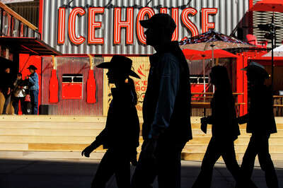 Four silhouttes of people walking pass a brightly red colored sign that reads "Ice House"