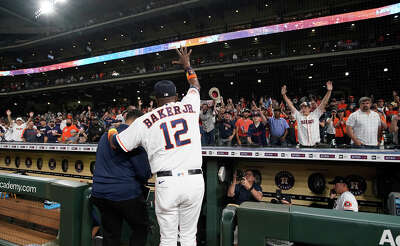 Baker's Jersey and number, 12, are seen from behind as his arm is outstetched waving to the crowd that is cheering for him as he descends into the dugout.