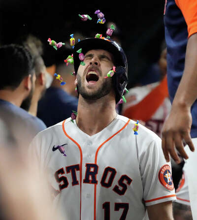 A baseball player yells as wrapped pieces of bubble gum rain over him in the dugout