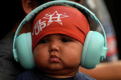 A round-cheeked baby wears equally rounded headphones to protest his ears