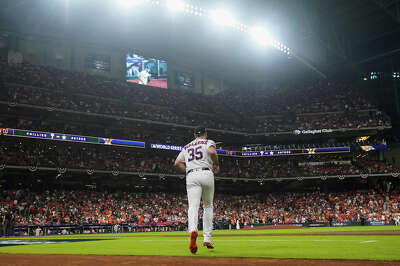 The stadium and its crowd and lights spread out in front of Verlander as he runs onto the field. 