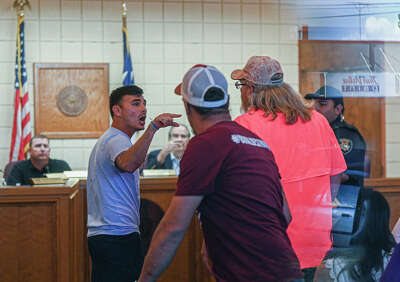 Angel Garza expressing his disapproval of an NRA-sponsored event to a supporter at a Hondo City Council meeting.