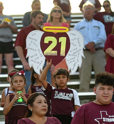 Child holding sign commemorating 21 students and teachers who died at Robb Elementary School in Uvalde.
