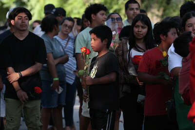 People lining up to pay their respects at a memorial at Robb Elementary School.
