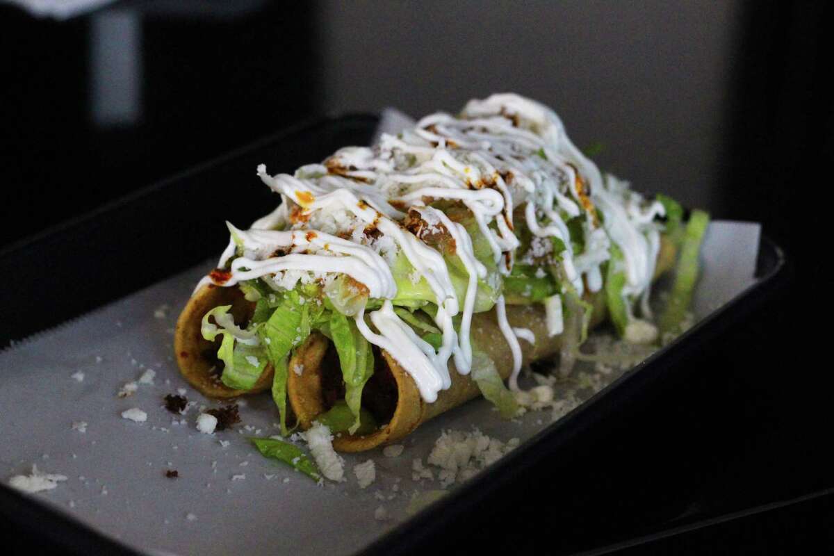 Tacos dorados covered with sour cream and lettuce