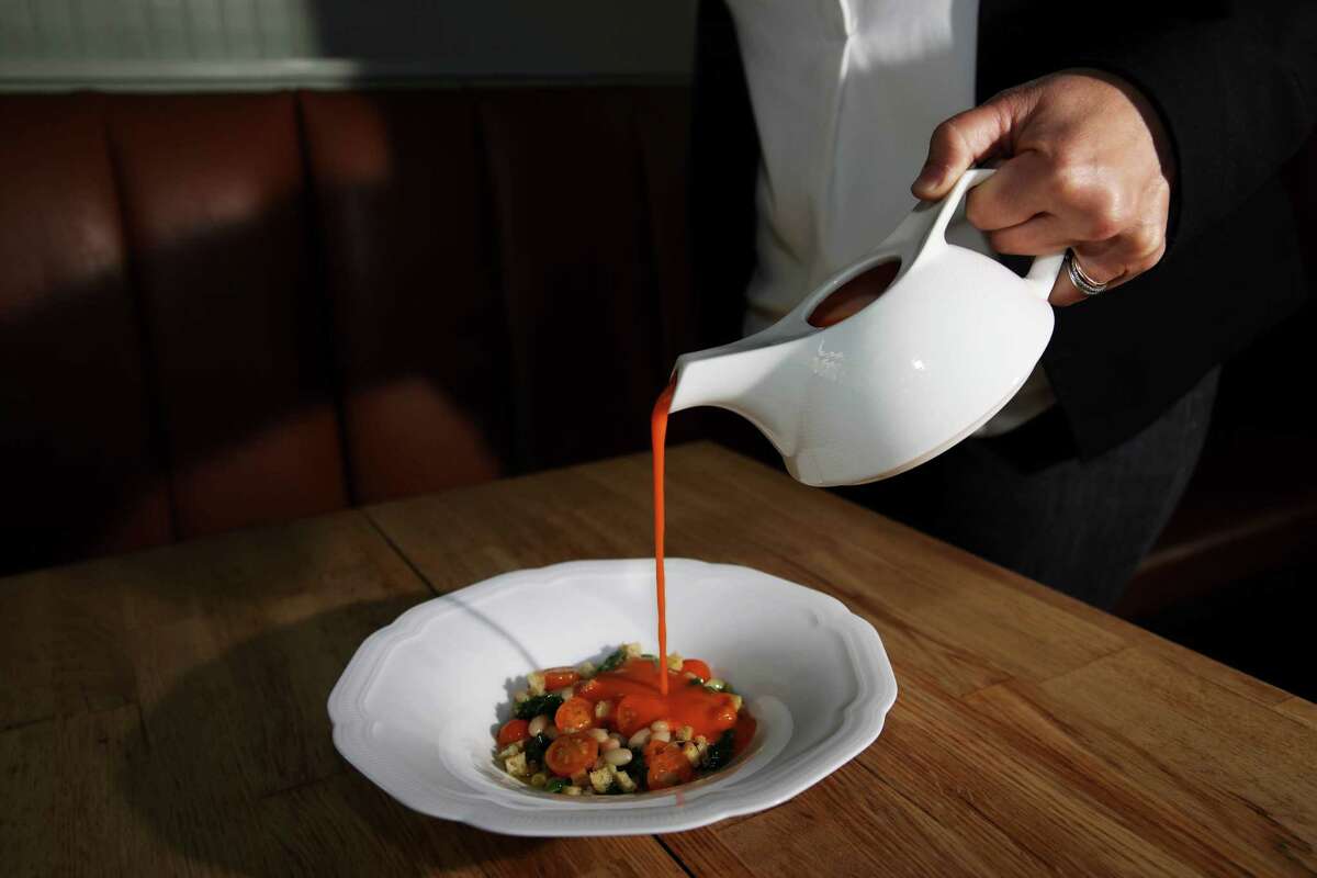 a sever pours tomato soup into a bowl.