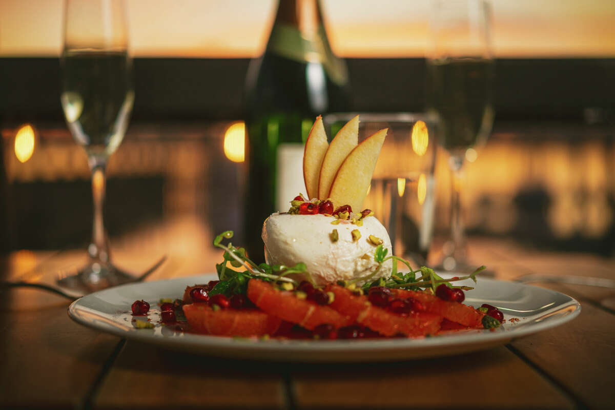 a seafood plate and wine glasses on a table. It is sunset, and water is in the out of focus background
