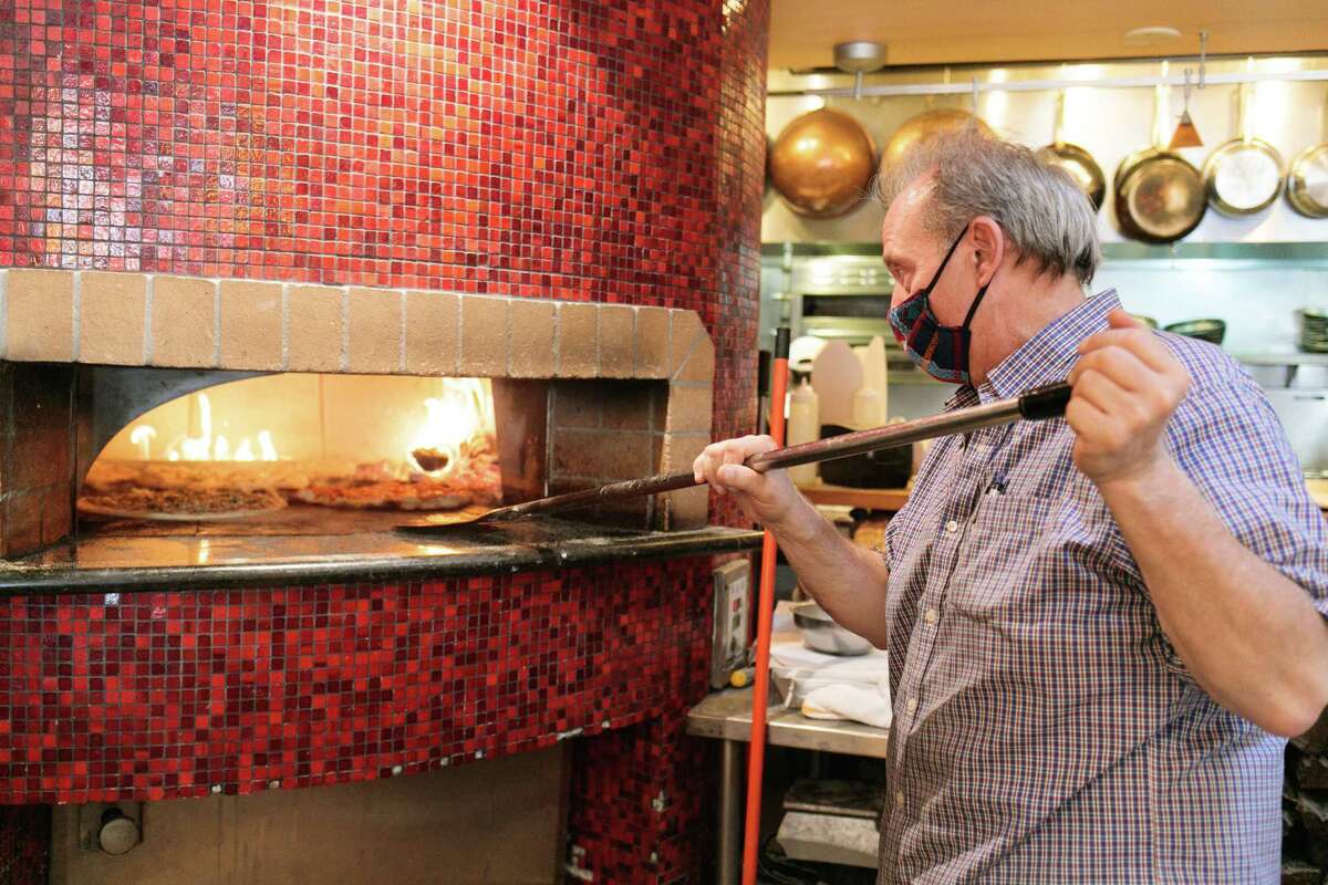 A man tending to a pizzas in an oven