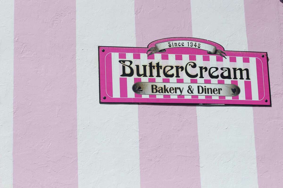 Pink and white background with logo that reads "Butter Cream Bakery & Diner." Box of doughnuts.