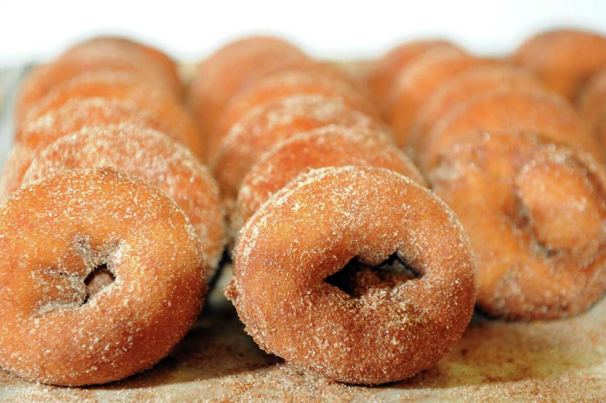 Rows of cider doughnuts dipped in cinnamon and sugar.