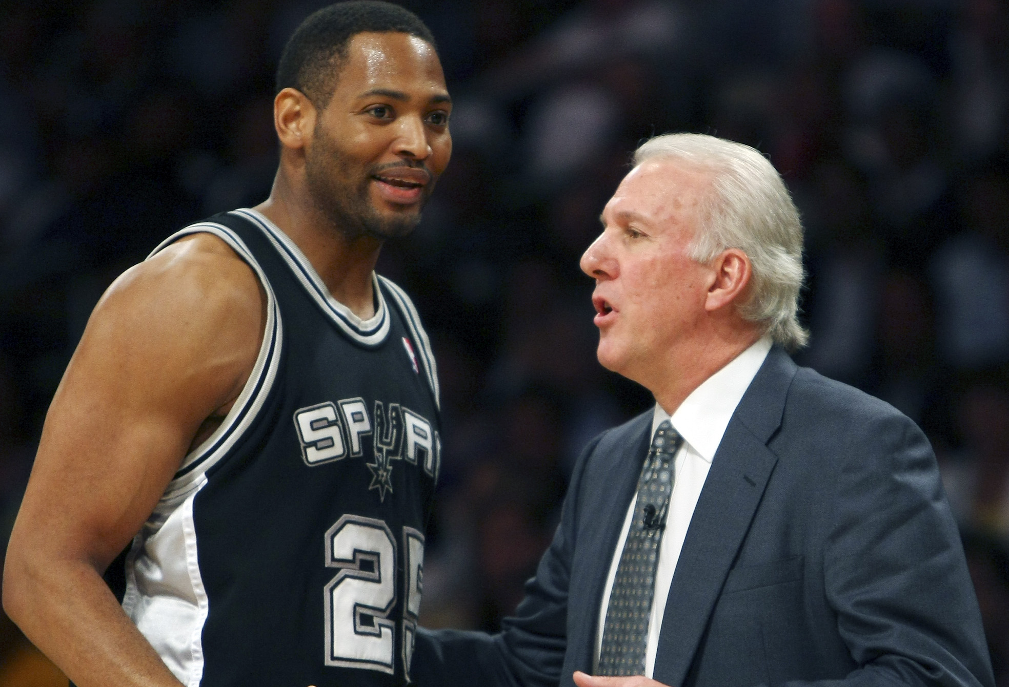Robery Horry speaking with Gregg Popovich on the sidelines during an NBA game.