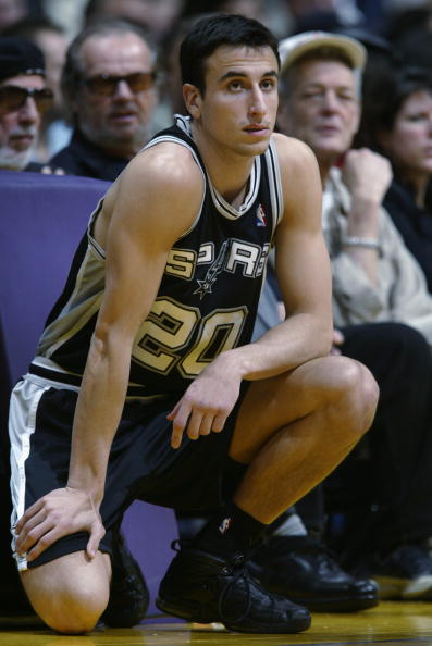 Manu Ginobili crouching on the sideline waiting to check into a game for the Spurs.