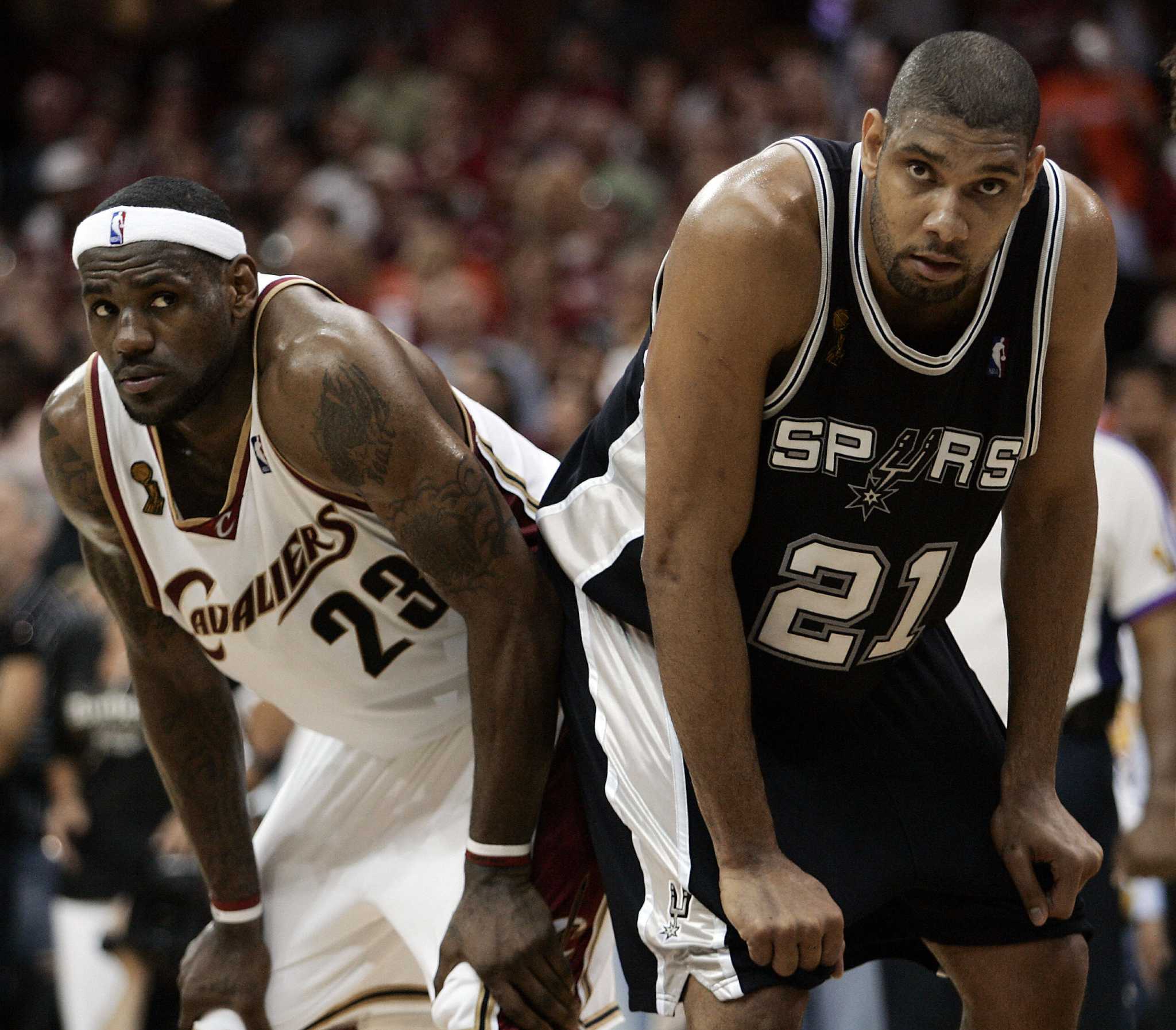 Tim Duncan and LeBron James bent over next to each other.