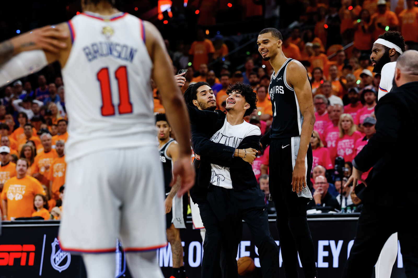 A fan runs onto the court to take a selfie with San Antonio Spurs center Victor Wembanyama during Game 1 of the NBA Finals against the New York Knicks. (Sam Owens/San Antonio Express-News)