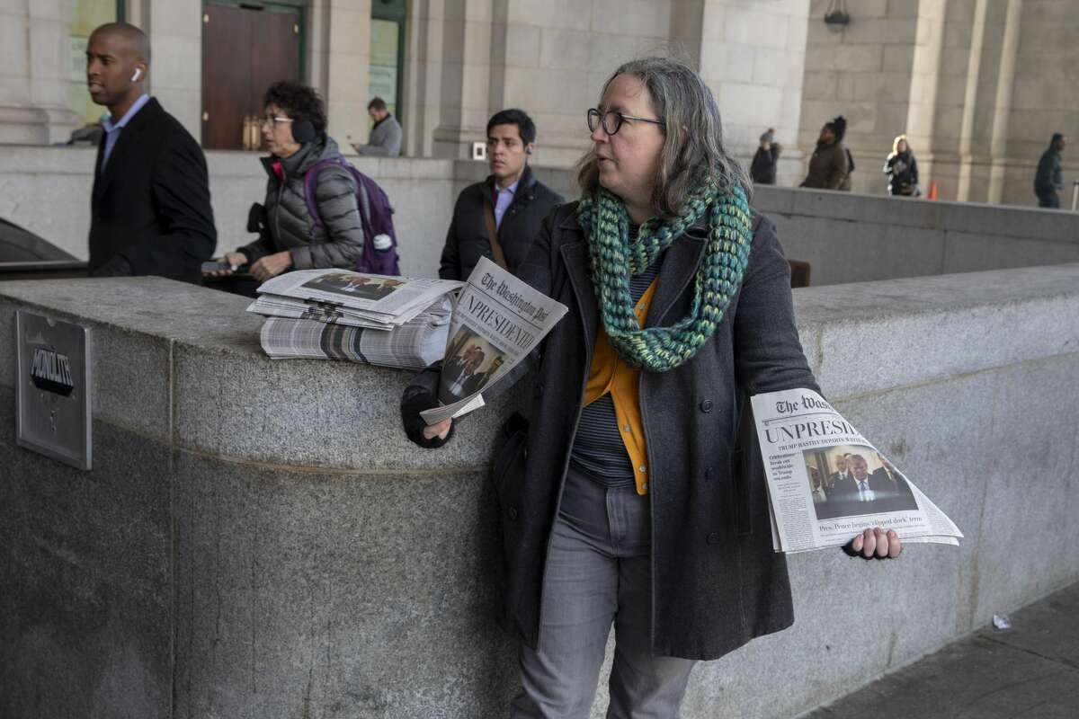 Volunteers distribute a lookalike "special edition" of The Washington Post, date May 1, which predicts Trump leaving office after months of women-led protests on January 16, 2019 in Washington, DC.
